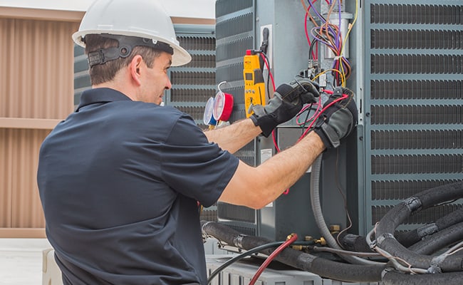 HVAC technician checking heating and cooling system pressures